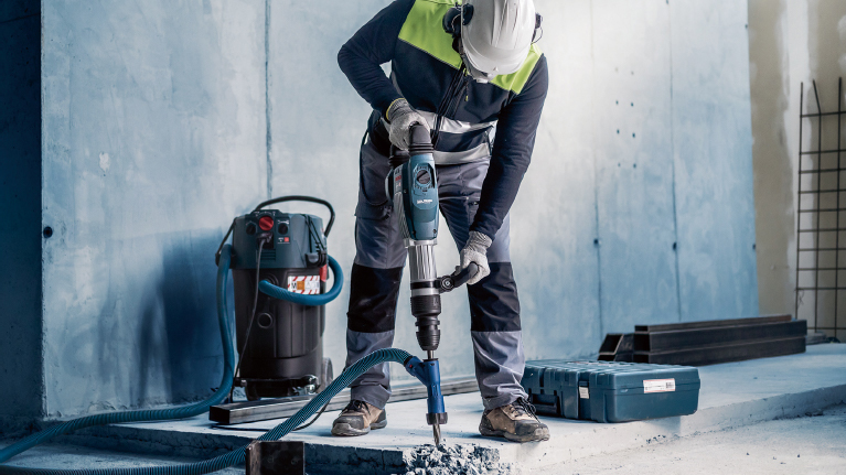 A worker with Bosch tools is drilling into a concrete floor.