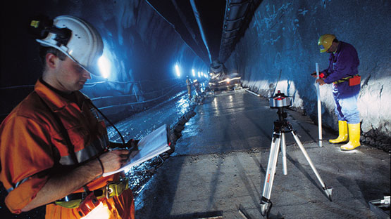 Worker in construction clothing checks plans in the tunnel with tools.