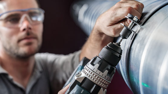 A craftsman is using a Bosch Professional cordless drill on a pipe.