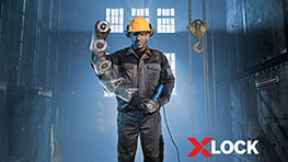 A man with a yellow helmet holds a Bosch XLOCK tool in a workshop.