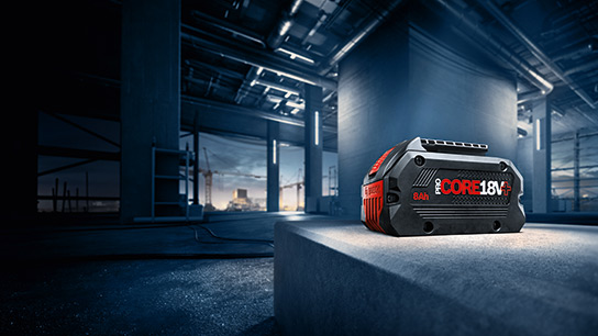 Benefits of 18V System A black Bosch Professional battery on a gray concrete block at a construction site.