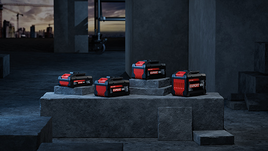 Four Bosch Professional batteries are standing on gray concrete blocks.