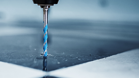 A blue drill penetrates a shiny surface.