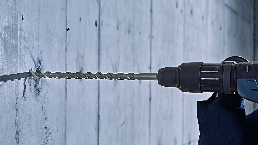 A Bosch Professional drill is being inserted into a concrete wall.