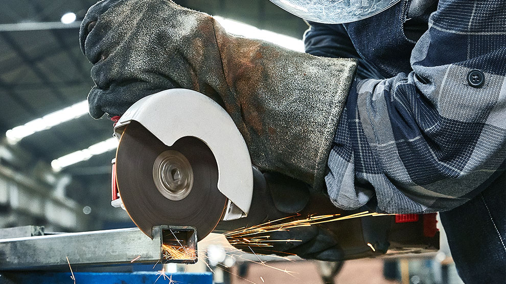 A worker is cutting metal with a Bosch cutting machine.