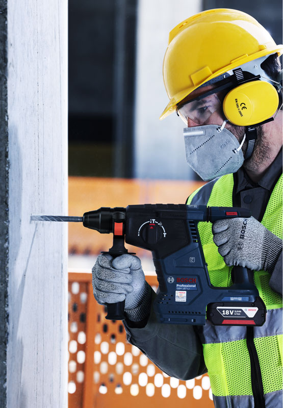 A worker with a yellow helmet is drilling with a Bosch Professional tool.
