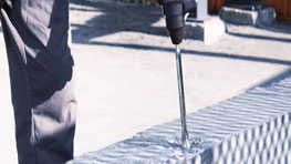 A craftsman is using a Bosch Professional drill on a brick.