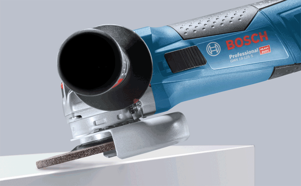 A blue Bosch Professional angle grinder is cutting a wooden board.